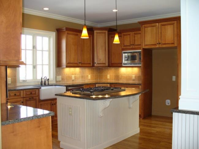 Inspiration for a transitional u-shaped medium tone wood floor kitchen remodel with a farmhouse sink, raised-panel cabinets, medium tone wood cabinets, granite countertops, beige backsplash, stone tile backsplash, stainless steel appliances, brown walls and an island