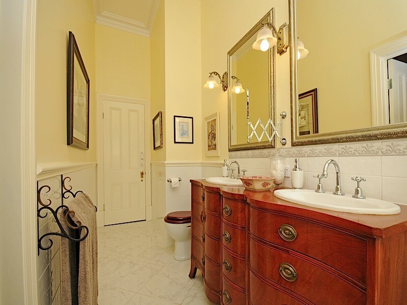 Traditional master bathroom in Perth with a drop-in sink, furniture-like cabinets, medium wood cabinets, wood benchtops, a freestanding tub, a one-piece toilet, white tile, porcelain tile, yellow walls and porcelain floors.