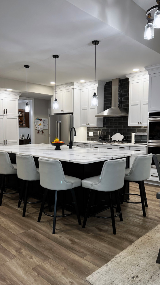 Example of a large transitional single-wall vinyl floor and beige floor eat-in kitchen design with a farmhouse sink, shaker cabinets, white cabinets, quartz countertops, black backsplash, subway tile backsplash, stainless steel appliances, an island and white countertops