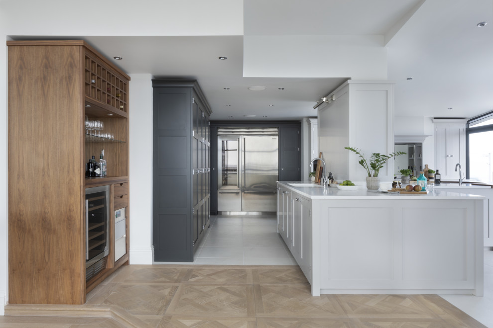 Inspiration for a large classic grey and black l-shaped kitchen/diner in London with a submerged sink, shaker cabinets, grey cabinets, quartz worktops, mirror splashback, stainless steel appliances, porcelain flooring, an island, grey floors and white worktops.