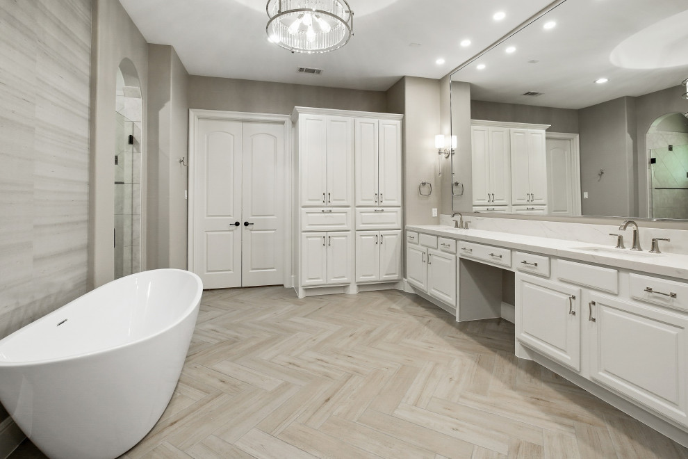 Photo of a large classic ensuite wet room bathroom in Houston with raised-panel cabinets, white cabinets, a freestanding bath, beige tiles, ceramic tiles, grey walls, ceramic flooring, a submerged sink, engineered stone worktops, grey floors, a hinged door, white worktops, double sinks, a built in vanity unit, a vaulted ceiling and wallpapered walls.