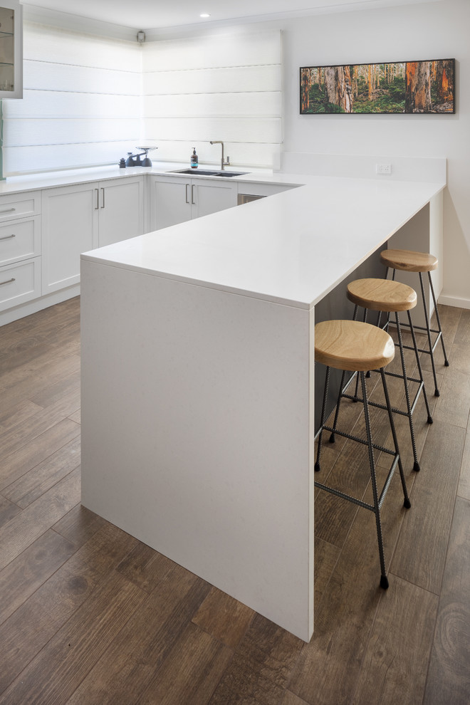 This is an example of a modern kitchen in Perth with flat-panel cabinets, white cabinets, quartz benchtops, ceramic floors, white benchtop and brown floor.
