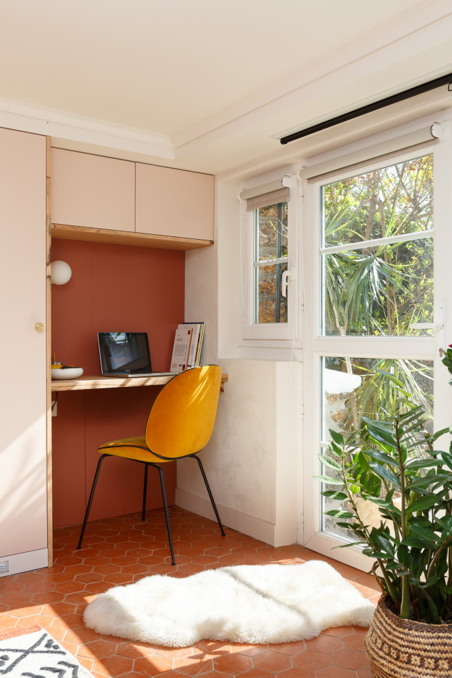 На фото: рабочее место среднего размера в средиземноморском стиле с розовыми стенами, полом из терракотовой плитки, встроенным рабочим столом и красным полом