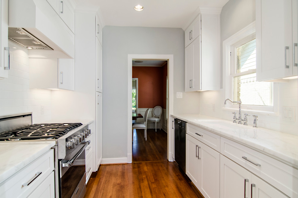 Example of a transitional galley eat-in kitchen design in Dallas with an undermount sink, shaker cabinets, white cabinets, marble countertops, white backsplash, subway tile backsplash and stainless steel appliances