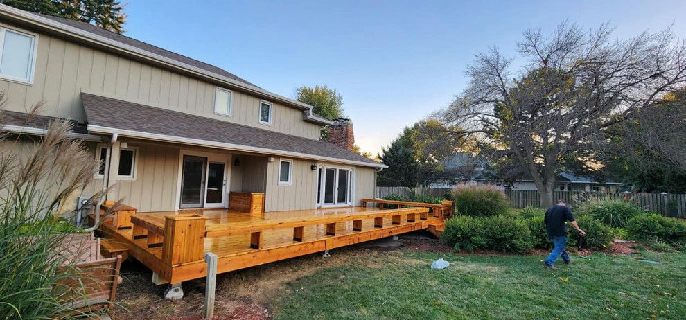 Example of a huge mountain style backyard ground level wood railing deck design in Omaha with no cover