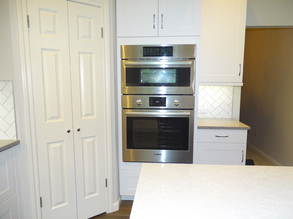 Example of a large transitional galley ceramic tile eat-in kitchen design in Austin with a drop-in sink, beaded inset cabinets, white cabinets, quartzite countertops, white backsplash, ceramic backsplash, stainless steel appliances and an island