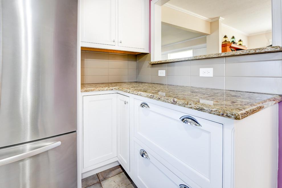 Mid-sized elegant u-shaped ceramic tile eat-in kitchen photo with an undermount sink, recessed-panel cabinets, white cabinets, granite countertops, beige backsplash, ceramic backsplash, stainless steel appliances and no island