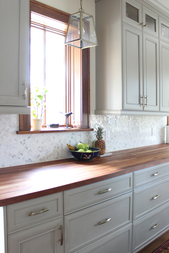 Example of a mid-sized transitional medium tone wood floor eat-in kitchen design with a drop-in sink, gray cabinets, concrete countertops, white backsplash, stainless steel appliances and an island