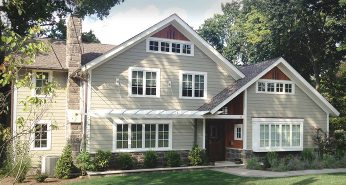 Large traditional two-storey grey house exterior in New York with vinyl siding, a gable roof and a shingle roof.