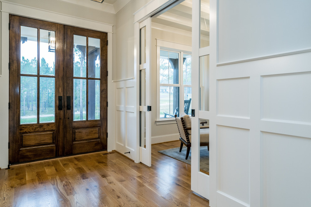 This is an example of a mid-sized country entry hall in Raleigh with grey walls, medium hardwood floors, a double front door, a brown front door and brown floor.