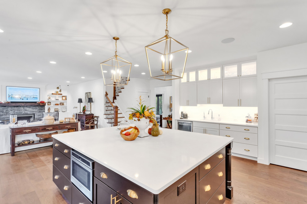 This is an example of a large arts and crafts u-shaped eat-in kitchen in Other with a farmhouse sink, shaker cabinets, white cabinets, quartzite benchtops, white splashback, subway tile splashback, stainless steel appliances, medium hardwood floors, with island, black floor and yellow benchtop.