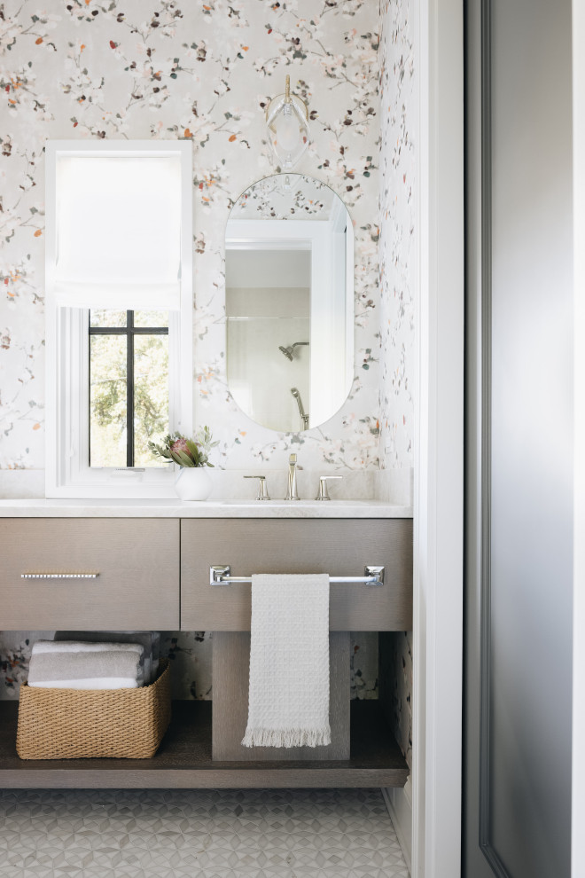 This is an example of a large transitional bathroom in Chicago with open cabinets, beige cabinets, a one-piece toilet, multi-coloured walls, a drop-in sink, multi-coloured floor, multi-coloured benchtops, a single vanity, a freestanding vanity and wallpaper.