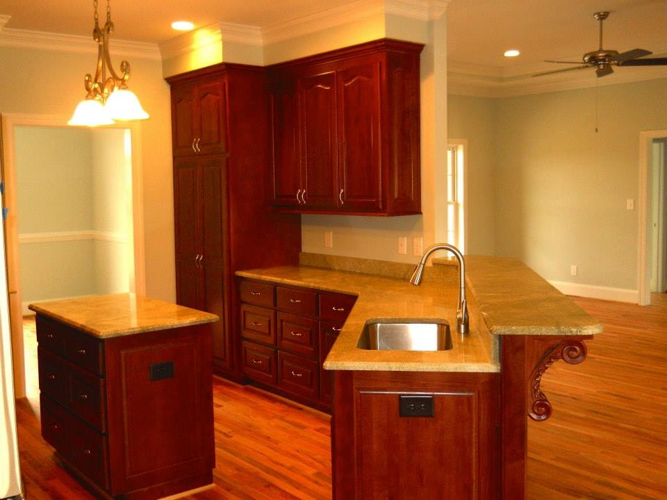 Photo of a mid-sized traditional open plan kitchen in Other with an undermount sink, raised-panel cabinets, medium wood cabinets, granite benchtops, stainless steel appliances, medium hardwood floors, with island and brown floor.