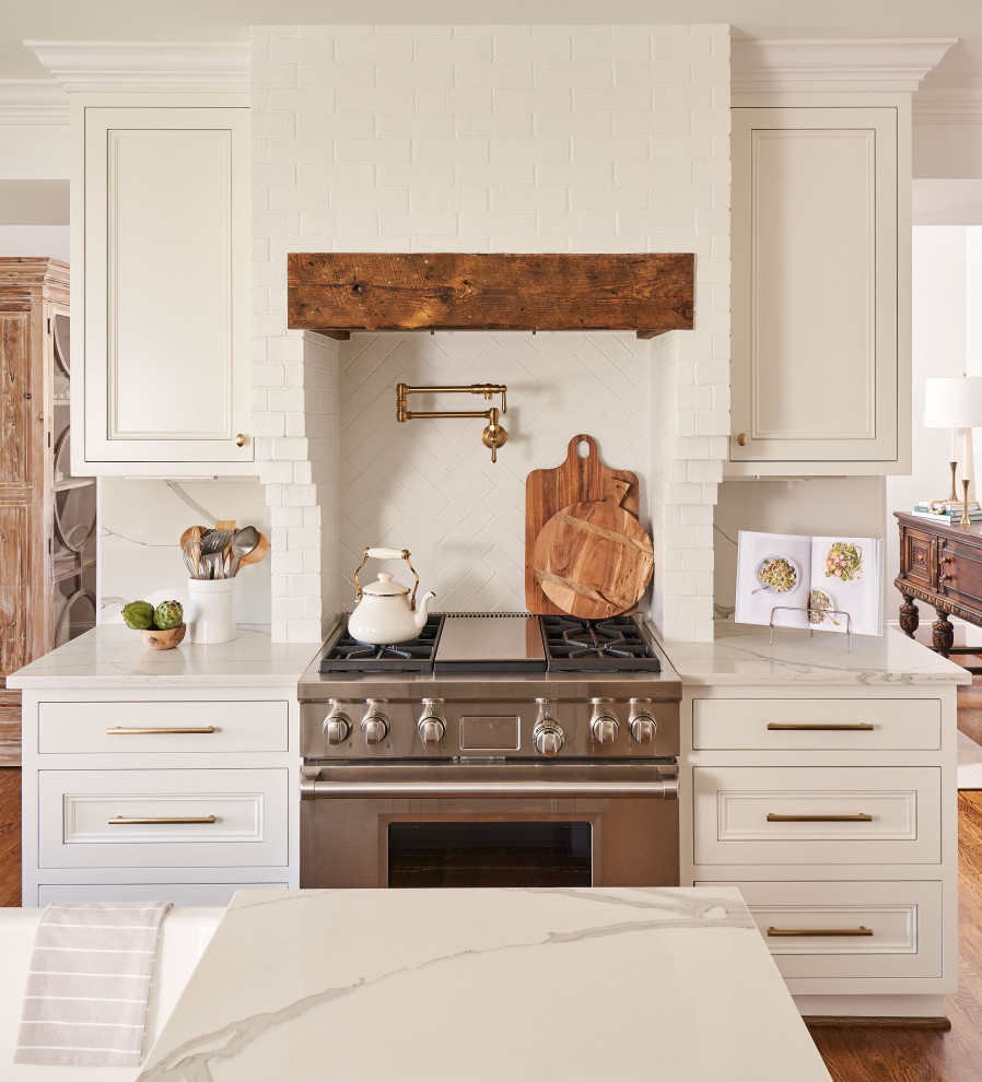 Idéer för ett vit kök, med vita skåp, marmorbänkskiva, vitt stänkskydd, stänkskydd i tegel, rostfria vitvaror, mörkt trägolv, en köksö och brunt golv