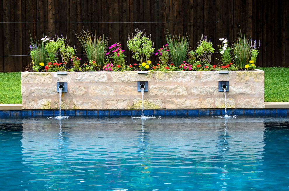 Example of a mid-sized transitional backyard rectangular pool fountain design in Dallas with decking