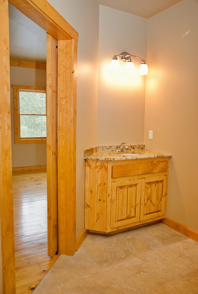 Example of a large mountain style kids' light wood floor and brown floor home design design with raised-panel cabinets, light wood cabinets, a two-piece toilet, beige walls, an undermount sink and laminate countertops