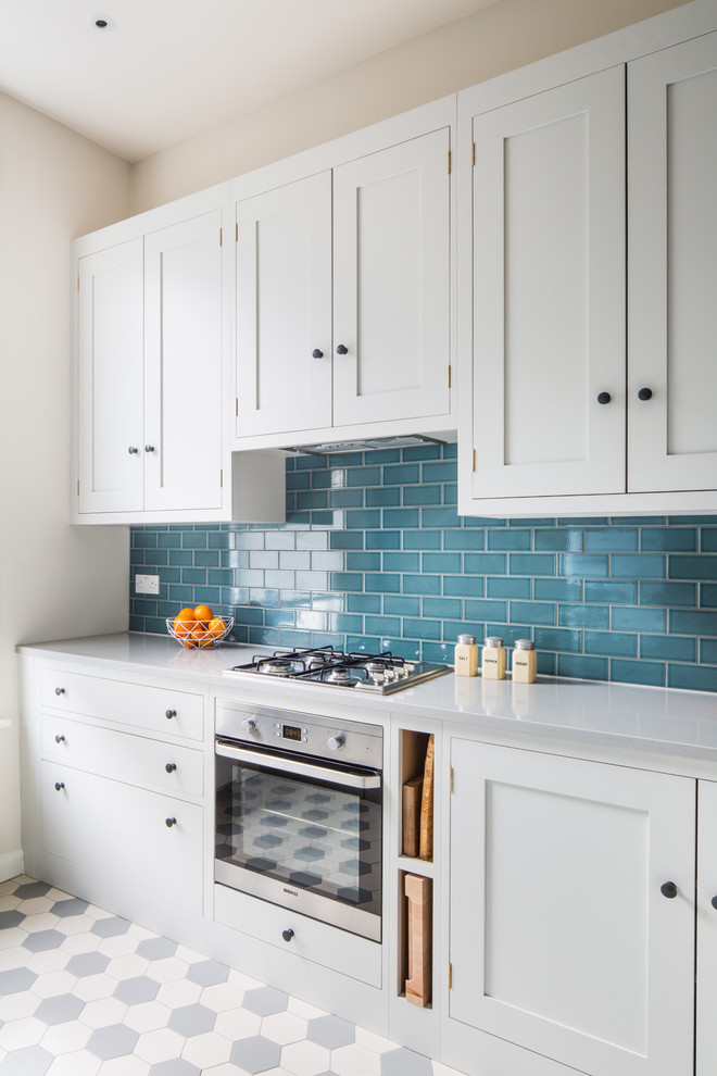 Design ideas for a small contemporary l-shaped open plan kitchen in London with a farmhouse sink, shaker cabinets, white cabinets, quartz benchtops, blue splashback, subway tile splashback, stainless steel appliances, ceramic floors, a peninsula and multi-coloured floor.