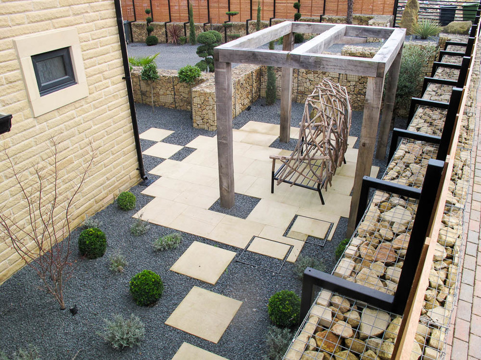 This is an example of a large contemporary backyard formal garden in Other with a retaining wall and decking.