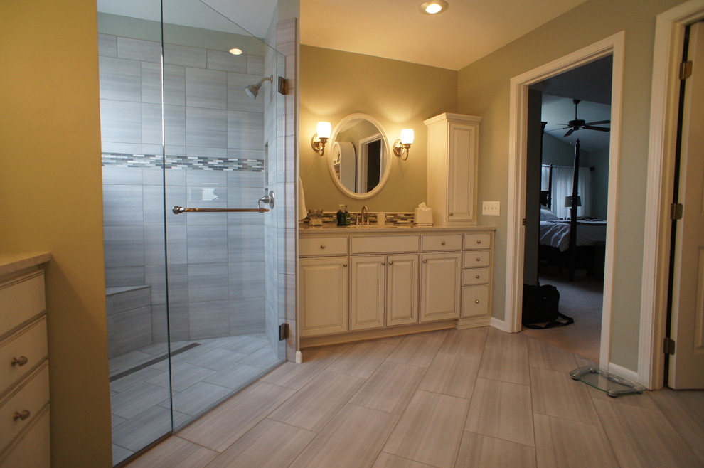 This is an example of a master bathroom in Kansas City with raised-panel cabinets, white cabinets, a curbless shower, multi-coloured tile, matchstick tile, grey walls, ceramic floors, an undermount sink and granite benchtops.
