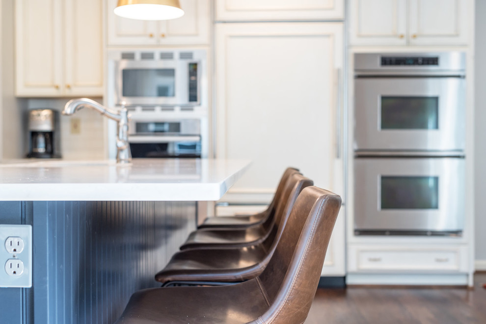 Inspiration for a transitional medium tone wood floor and brown floor kitchen remodel in DC Metro with an undermount sink, recessed-panel cabinets, white cabinets, granite countertops, white backsplash, subway tile backsplash, stainless steel appliances, an island and white countertops