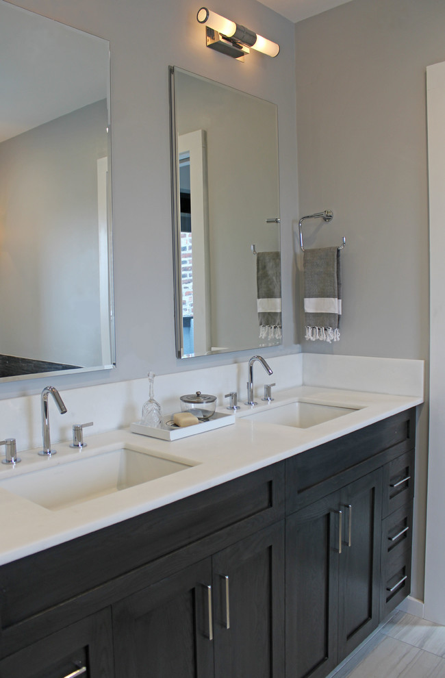 Photo of a mid-sized transitional master bathroom in Boston with recessed-panel cabinets, dark wood cabinets, an undermount tub, an alcove shower, a two-piece toilet, multi-coloured tile, pebble tile, grey walls, porcelain floors, an undermount sink, engineered quartz benchtops, grey floor, a hinged shower door and white benchtops.