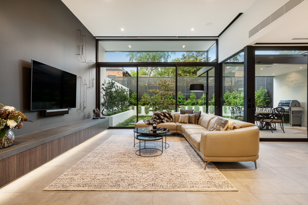 Photo of a contemporary open concept living room in Melbourne with grey walls, a wall-mounted tv and grey floor.