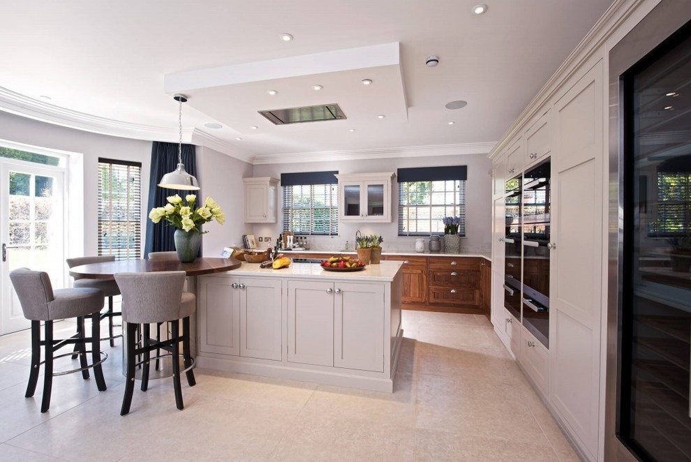 Design ideas for a large contemporary l-shaped open plan kitchen in Sussex with beige cabinets, marble benchtops, beige splashback, black appliances and with island.