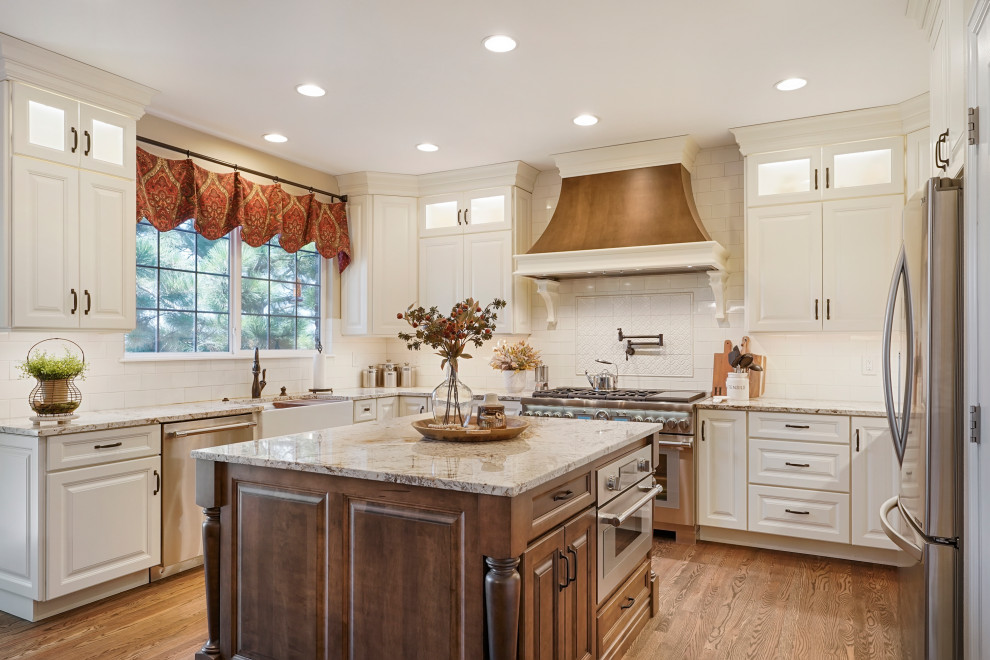 Large elegant u-shaped eat-in kitchen photo in Denver with a farmhouse sink, raised-panel cabinets, white cabinets, white backsplash, subway tile backsplash, stainless steel appliances, an island and beige countertops