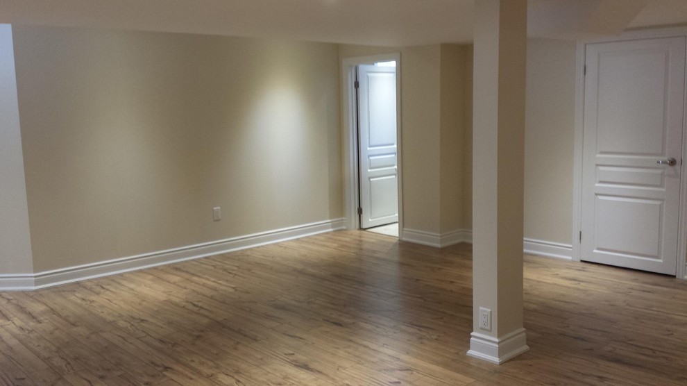 Photo of a large traditional fully buried basement in Toronto with beige walls, light hardwood floors, no fireplace and beige floor.