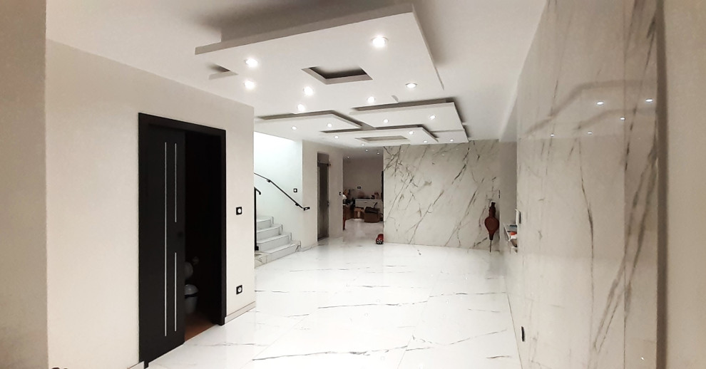 На фото: подземный, большой подвал в современном стиле с белыми стенами, полом из керамической плитки, белым полом и многоуровневым потолком с