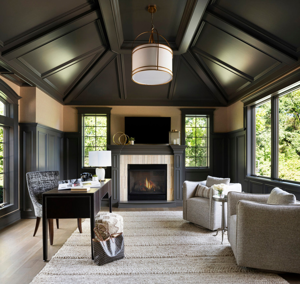 Transitional study room in Minneapolis with beige walls, medium hardwood floors, a standard fireplace, a stone fireplace surround, a freestanding desk, brown floor, vaulted and panelled walls.