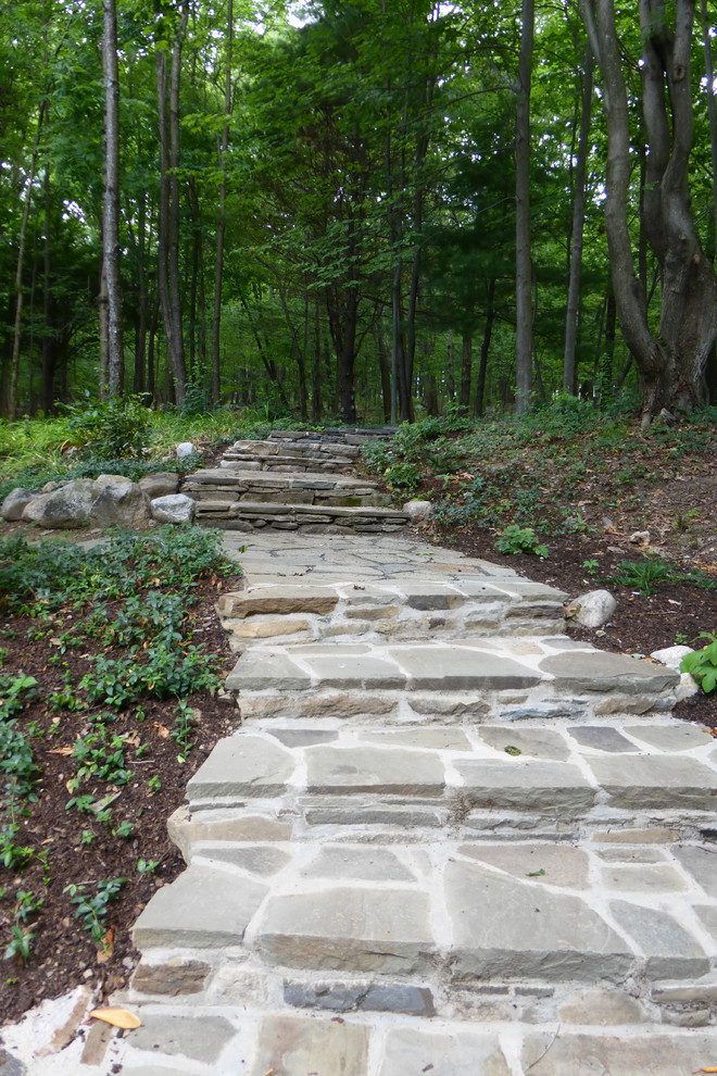 Inspiration for an expansive country backyard shaded xeriscape for summer in New York with natural stone pavers and a retaining wall.