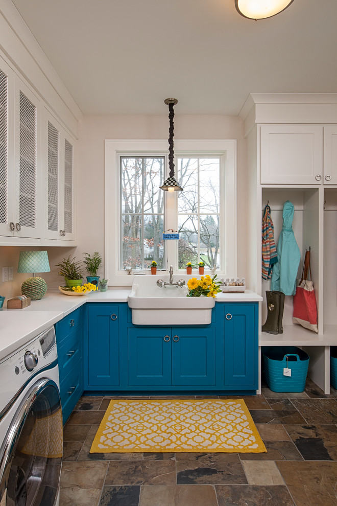 Design ideas for a transitional laundry room in Detroit with a farmhouse sink, shaker cabinets, blue cabinets, quartz benchtops, beige walls, slate floors, a side-by-side washer and dryer, brown floor and white benchtop.