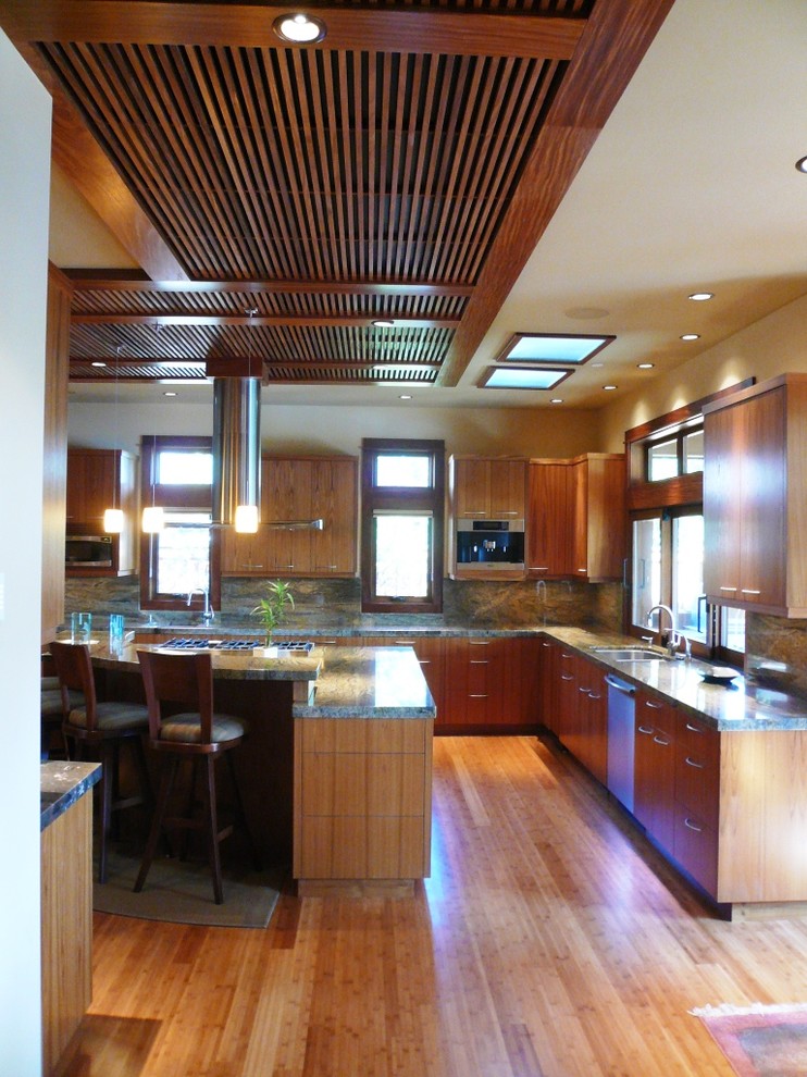 Inspiration for a large asian u-shaped open plan kitchen in Seattle with an undermount sink, flat-panel cabinets, medium wood cabinets, granite benchtops, green splashback, stone slab splashback, stainless steel appliances, medium hardwood floors and with island.