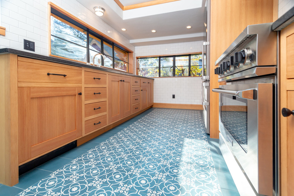 Inspiration for a mid-sized arts and crafts galley separate kitchen in Portland with an integrated sink, recessed-panel cabinets, light wood cabinets, quartzite benchtops, white splashback, subway tile splashback, stainless steel appliances, cement tiles, no island, blue floor and black benchtop.