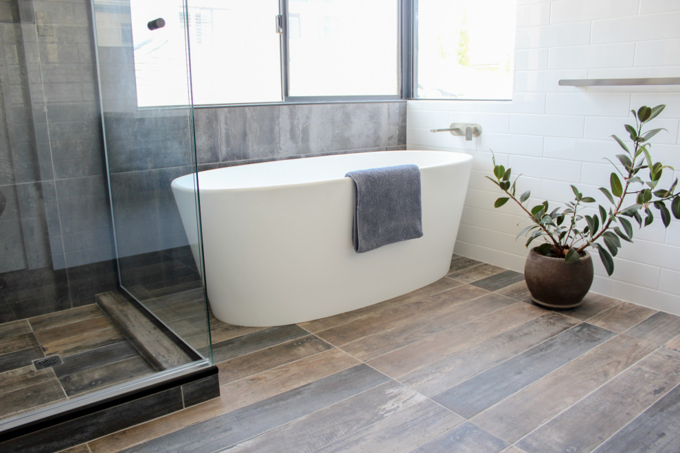 Photo of a large modern master bathroom in Perth with shaker cabinets, blue cabinets, a freestanding tub, a curbless shower, white tile, ceramic tile, multi-coloured walls, wood-look tile, a vessel sink, engineered quartz benchtops, multi-coloured floor, a hinged shower door and white benchtops.