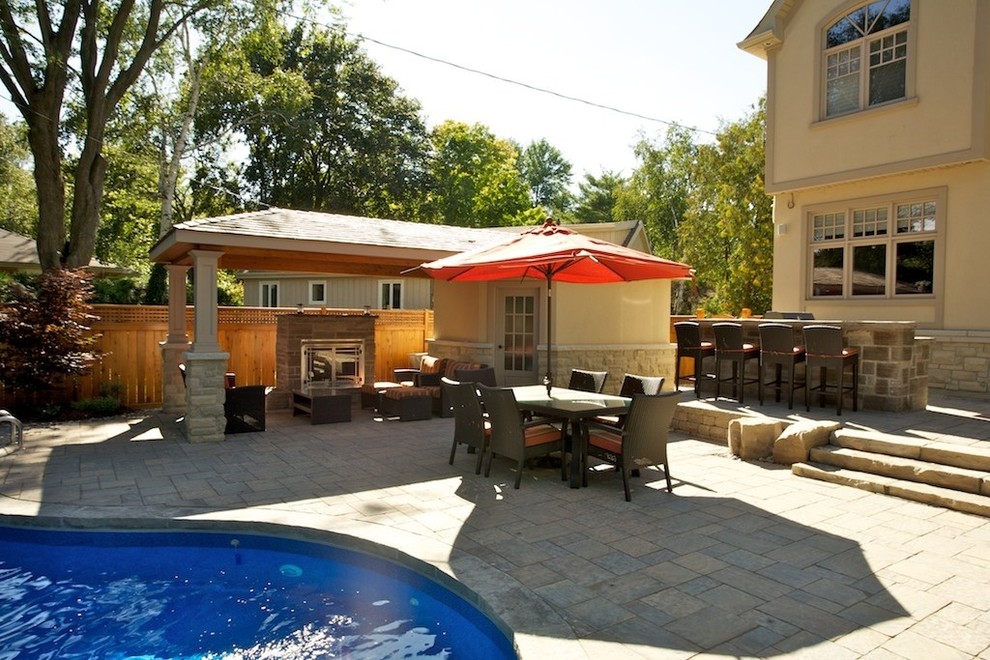 Photo of a mid-sized traditional backyard patio in Toronto with a fire feature, concrete pavers and a roof extension.