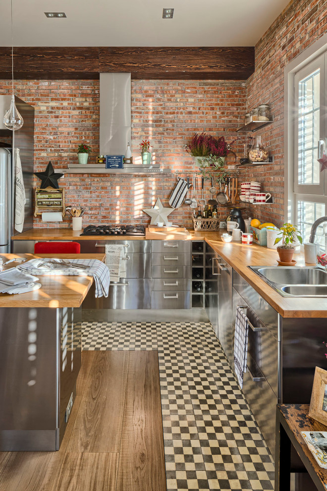 Inspiration for a large industrial l-shaped eat-in kitchen in Madrid with a drop-in sink, flat-panel cabinets, stainless steel cabinets, wood benchtops, stainless steel appliances, medium hardwood floors and with island.
