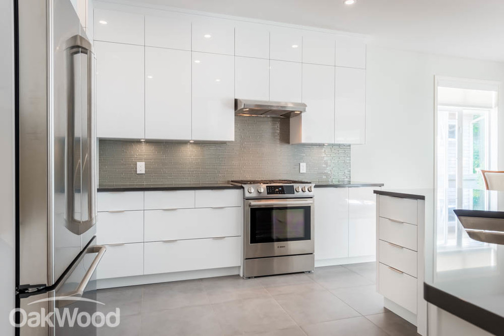 Large contemporary l-shaped separate kitchen in Ottawa with an undermount sink, flat-panel cabinets, white cabinets, tile benchtops, grey splashback, glass tile splashback, stainless steel appliances, ceramic floors and a peninsula.