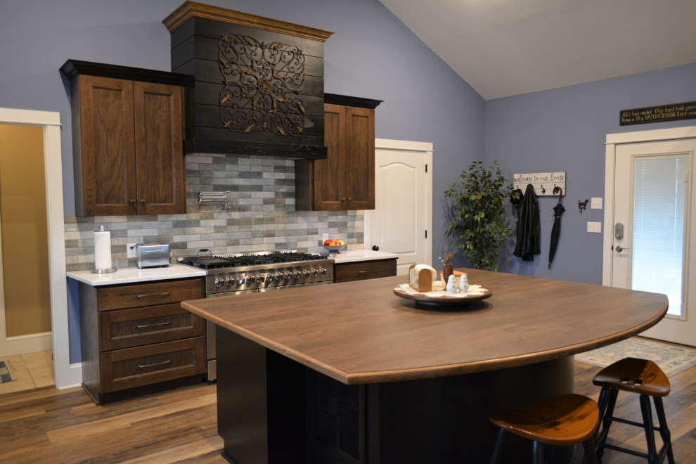 Inspiration for a huge transitional l-shaped brown floor and vaulted ceiling eat-in kitchen remodel with a drop-in sink, flat-panel cabinets, dark wood cabinets, quartz countertops, beige backsplash, ceramic backsplash, stainless steel appliances, an island and white countertops