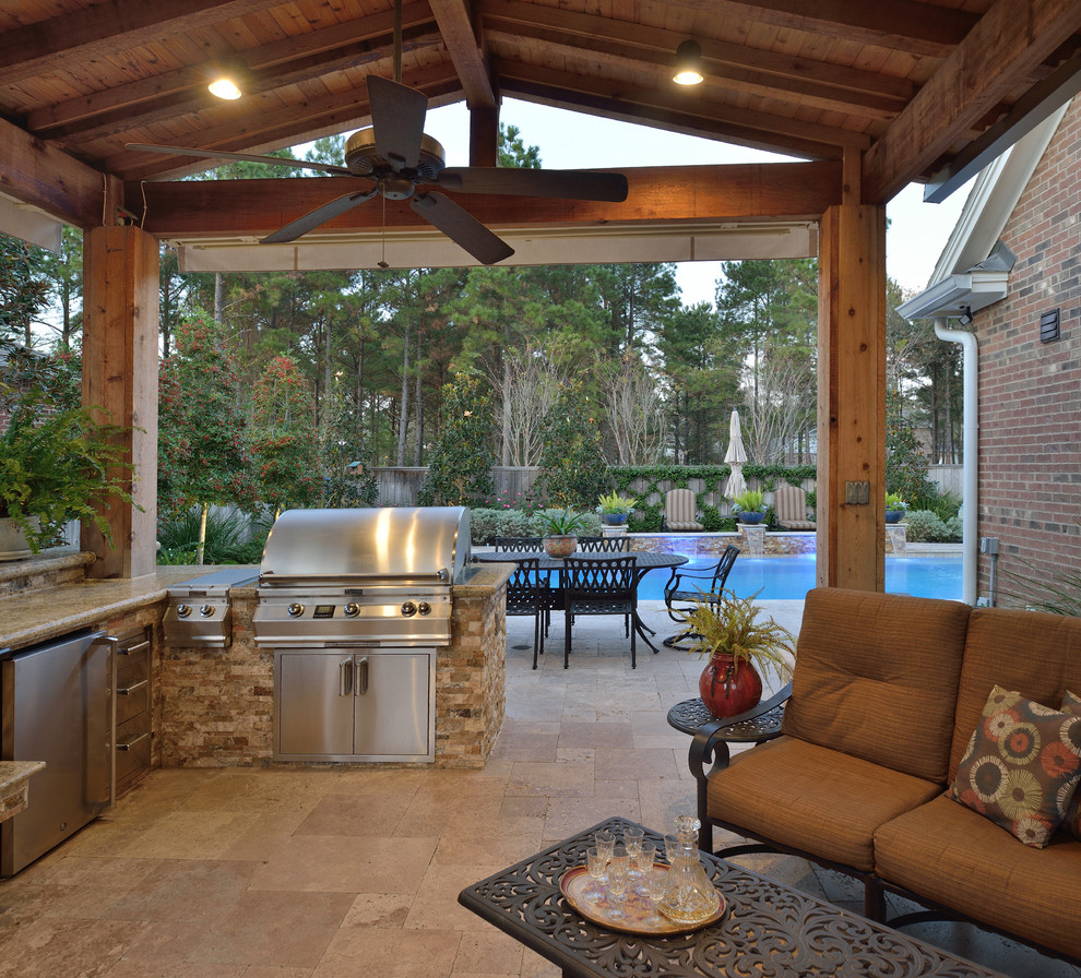 Large transitional backyard patio in Houston with natural stone pavers and an awning.