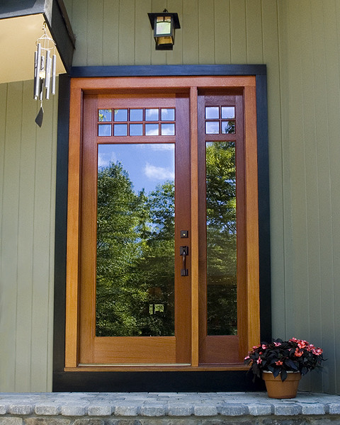 This is an example of a traditional front door in New York with green walls, granite floors and a light wood front door.