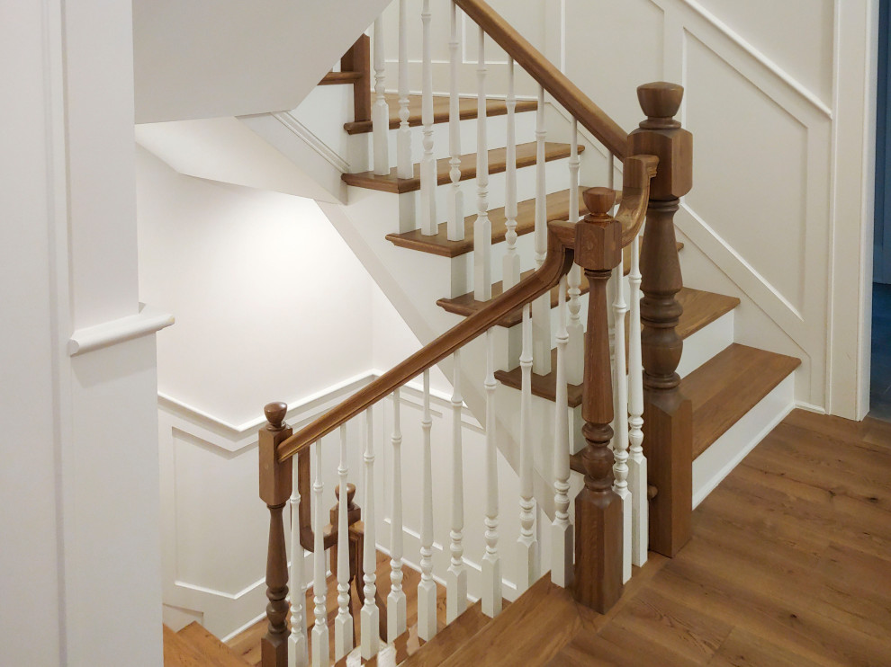 Modelo de escalera en U clásica de tamaño medio con escalones de madera, contrahuellas de madera pintada, barandilla de madera y boiserie