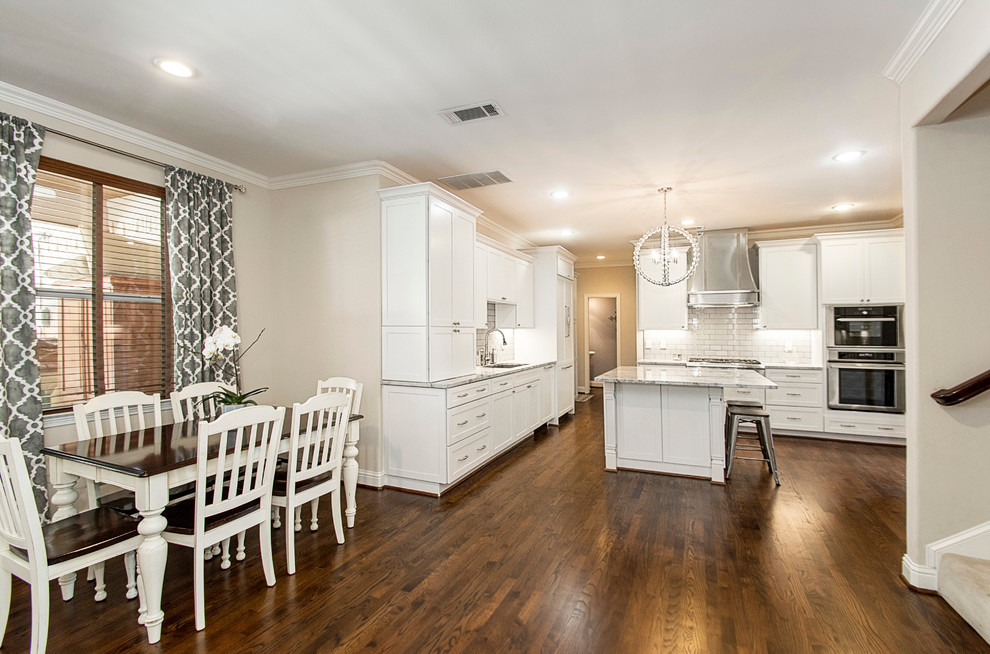 Example of a large transitional u-shaped medium tone wood floor open concept kitchen design in Dallas with an undermount sink, shaker cabinets, white cabinets, quartz countertops, white backsplash, porcelain backsplash, stainless steel appliances and an island