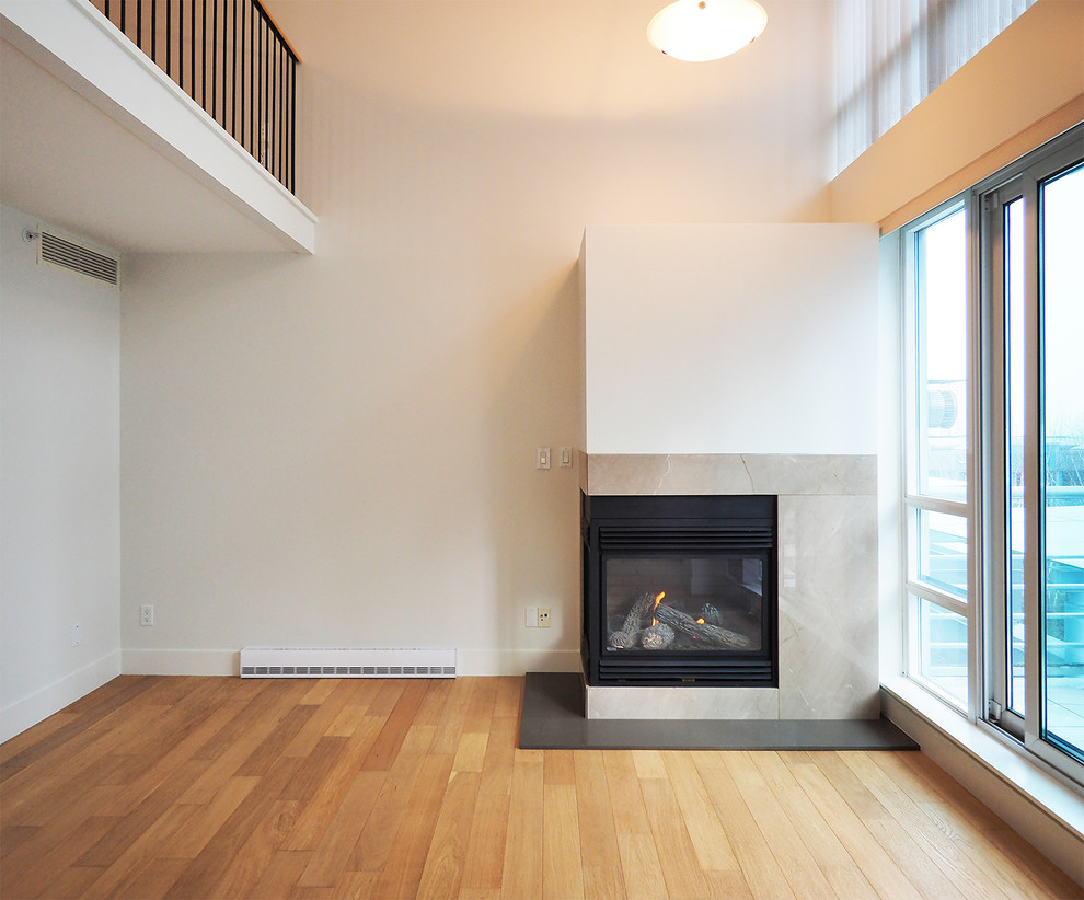 Design ideas for a mid-sized modern formal loft-style living room in Vancouver with white walls, medium hardwood floors, a corner fireplace, a tile fireplace surround and no tv.