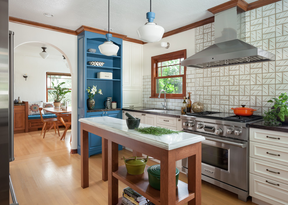 This is an example of a traditional separate kitchen in Seattle with an undermount sink, white cabinets, white splashback, stainless steel appliances, medium hardwood floors, with island, brown floor, grey benchtop and recessed-panel cabinets.