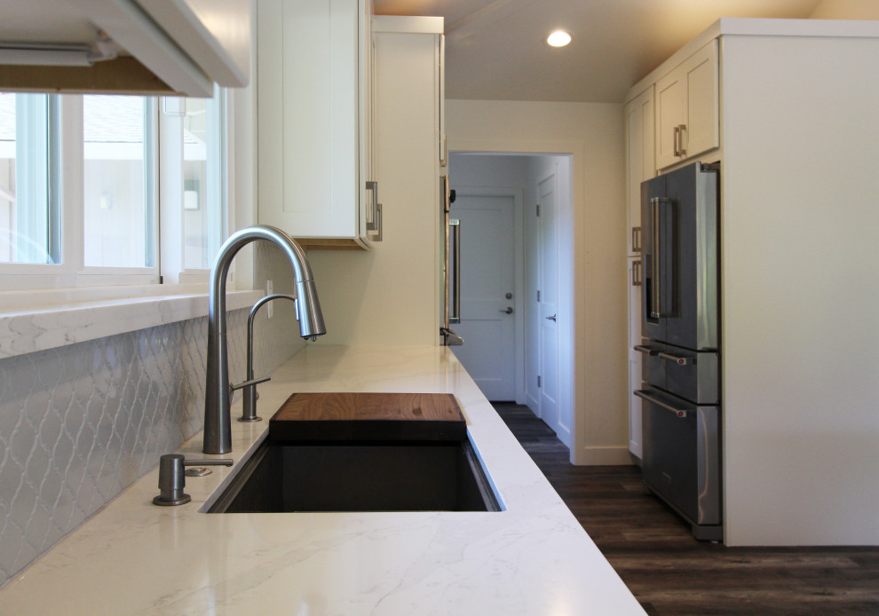 Inspiration for a large transitional single-wall vinyl floor and brown floor open concept kitchen remodel with an undermount sink, shaker cabinets, white cabinets, quartz countertops, gray backsplash, ceramic backsplash, stainless steel appliances, an island and white countertops