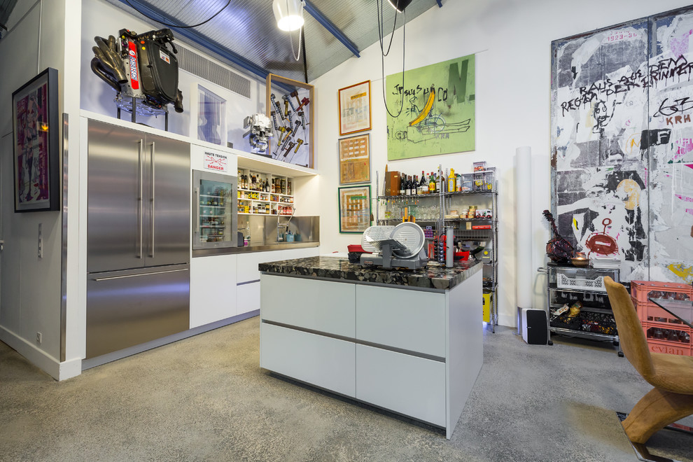 Immagine di una cucina bohémian con ante lisce, ante bianche, elettrodomestici in acciaio inossidabile e pavimento in cemento