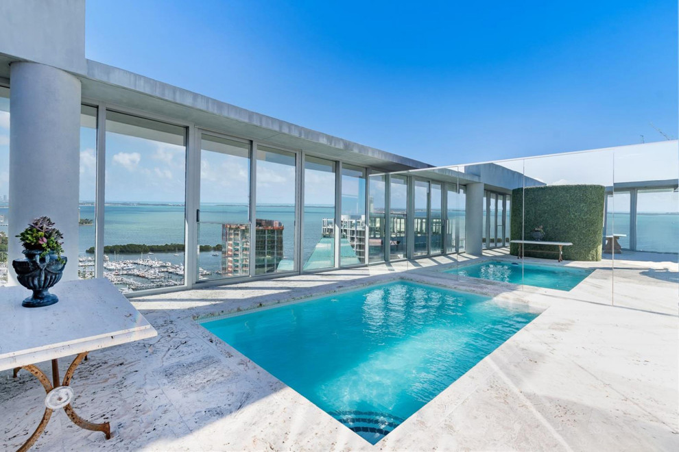 Large contemporary rooftop rectangular aboveground pool in Miami with with privacy feature and natural stone pavers.