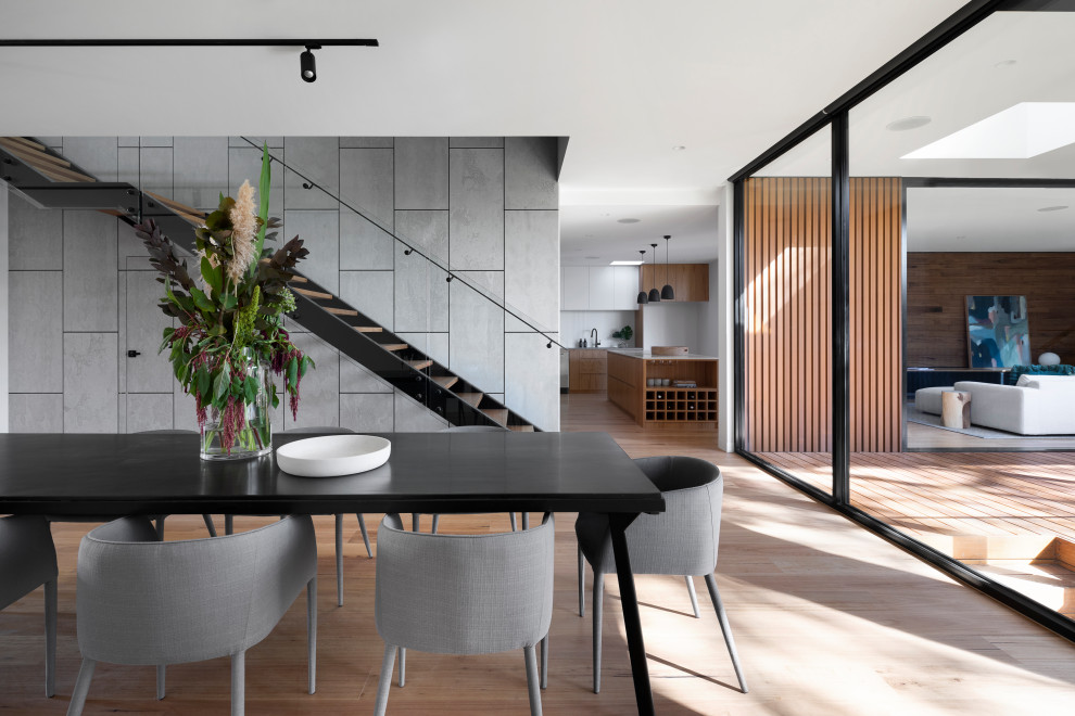 This is an example of a large contemporary open plan dining in Melbourne with grey walls, medium hardwood floors, brown floor, a ribbon fireplace, a tile fireplace surround and panelled walls.